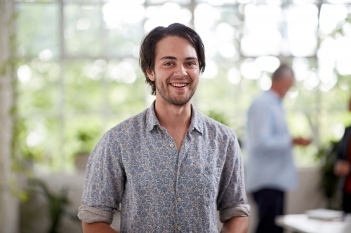 Young professional man standing in an open plan office - Australian Stock Image