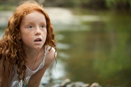 Young redheaded girl by the riverside