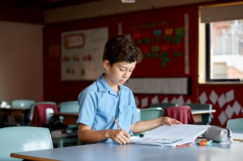 Young school boy in classroom working on homework - Australian Stock Image