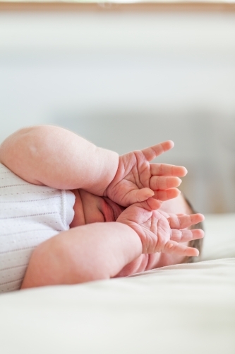 Young sleepy baby rubbing eyes with hands - Australian Stock Image