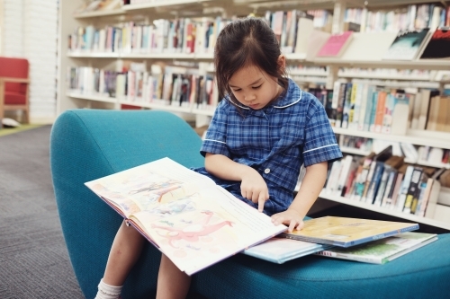 Young student girl reading in library - Australian Stock Image