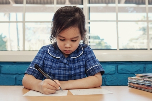 Young student girl writing in libary - Australian Stock Image