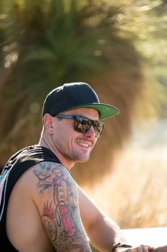 Young tattooed guy wearing sunnies and a cap - Australian Stock Image