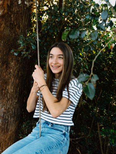 Young teenage girl hanging on a rope swing on a tree. - Australian Stock Image