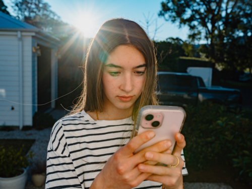 Young teenage girl holding a mobile device. - Australian Stock Image