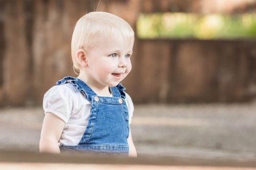 Young toddler girl smiling playing in garden - Australian Stock Image