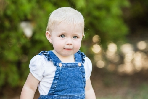 Young toddler girl with blonde hair outside in garden - Australian Stock Image