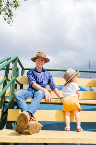 Young uncle sitting on grandstand seats with his toddler niece at local agricultural show