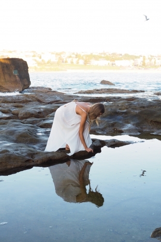 Young woman beside calm coastal rock pool