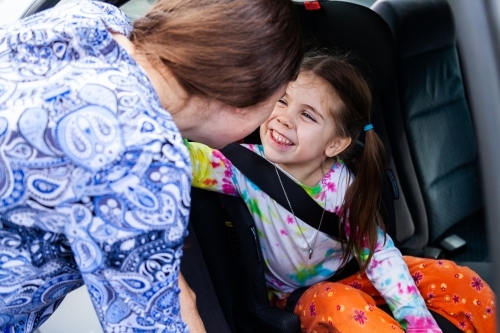 Young woman clicking child into car booster seat - Australian Stock Image