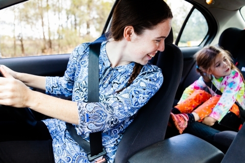 Young woman driving car with children in the back seats - Australian Stock Image