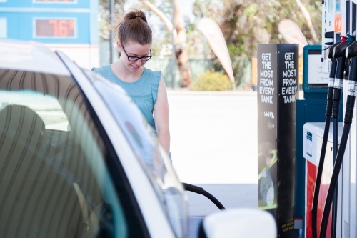 Young woman filling up car at petrol pump - Australian Stock Image