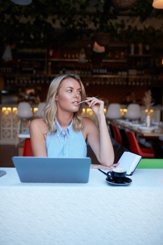 Young woman freelancing from her laptop at cafe - Australian Stock Image