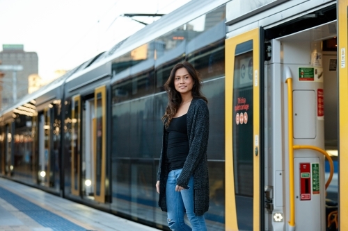 Young woman getting off train at train station - Australian Stock Image