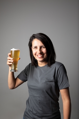 Young woman holding a glass of beer, relaxed and happy - Australian Stock Image