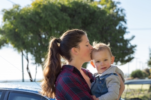 Young woman holding and kissing toddler