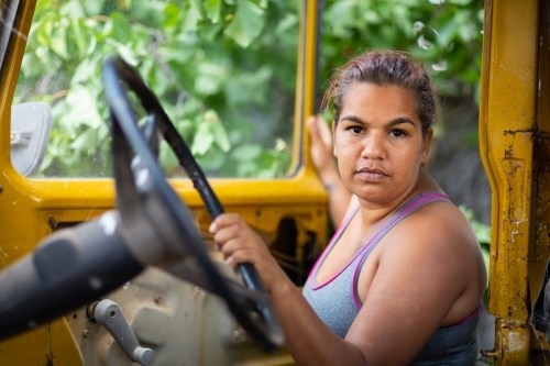 Young woman holding the steering wheel of an old vehicle - Australian Stock Image