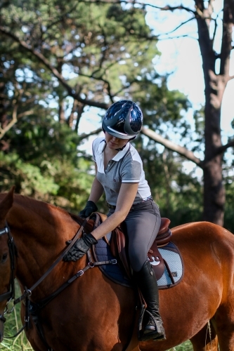 Young woman horse riding in park - Australian Stock Image
