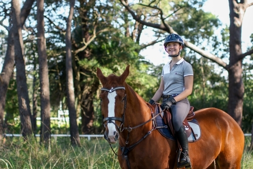 Young woman horse riding in park - Australian Stock Image
