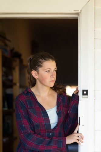 Young woman in checked shirt looking out of doorway