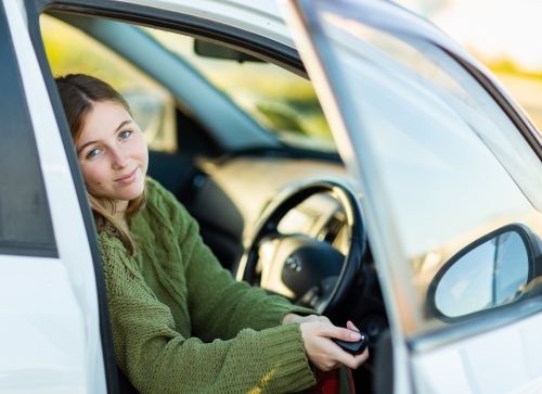 young woman in drivers seat of car with car key - Australian Stock Image