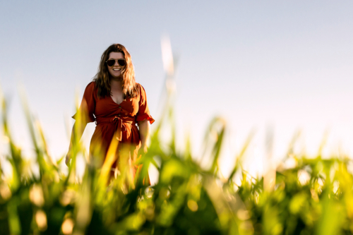 Young woman in red dress twirling in a green field - Australian Stock Image