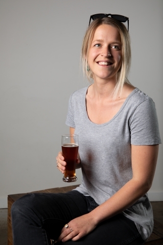 Young woman in relaxed pose wearing casual gear, holding a beer