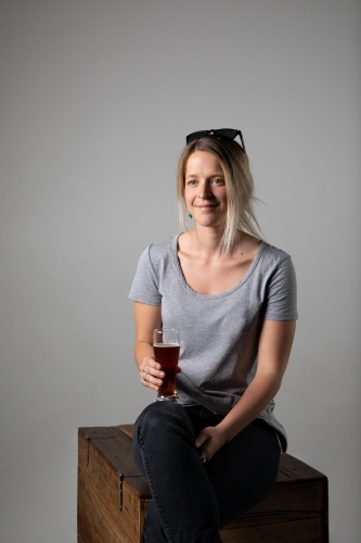 Young woman in relaxed pose wearing casual gear, holding a glass of beer