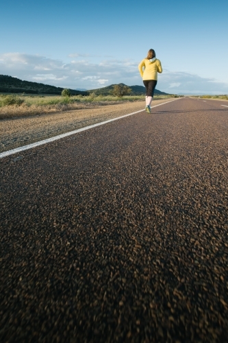 Young woman jogging on a country road - Australian Stock Image