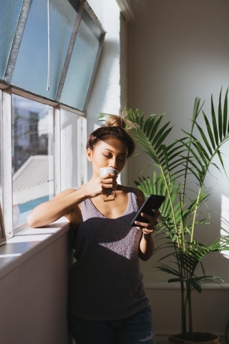 Young woman looking at her mobile phone with a coffee
