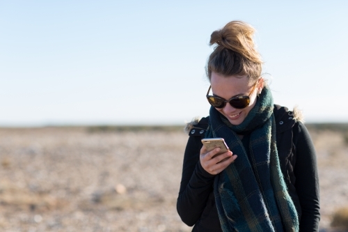 Young woman looking at smartphone in arid landscape - Australian Stock Image