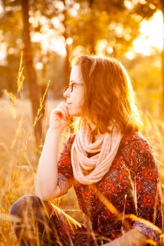 young woman looking away dreaming in golden sunset light - Australian Stock Image
