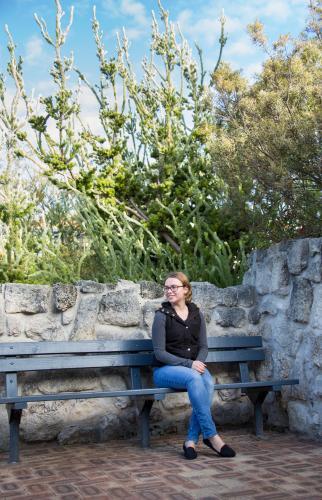 Young woman on bench near stone wall - Australian Stock Image