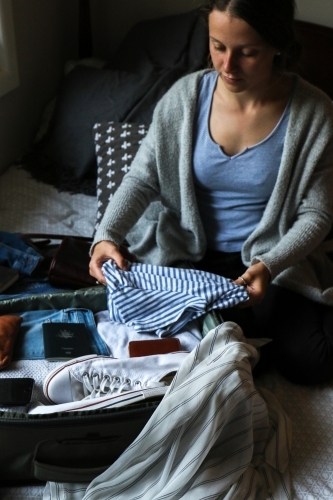 Young woman packing her bag ready to travel - Australian Stock Image