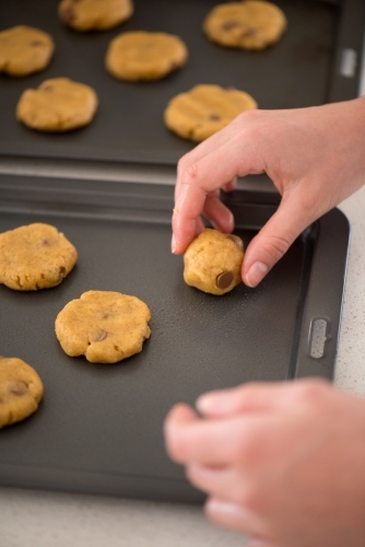 Young woman placing cookie dough onto baking trays