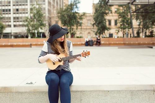 Young woman playing a ukulele on city street
