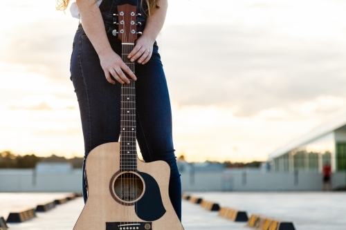 Young woman posing with guitar outside - Australian Stock Image