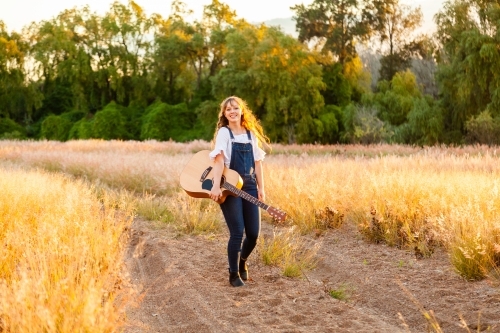 Young woman posing with guitar outside - Australian Stock Image