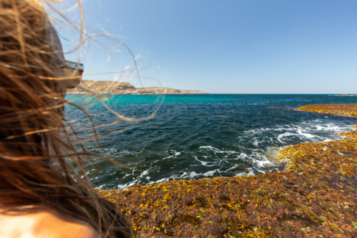 Young woman's view of rugged coastline on a windy summer day in South Australia - Australian Stock Image