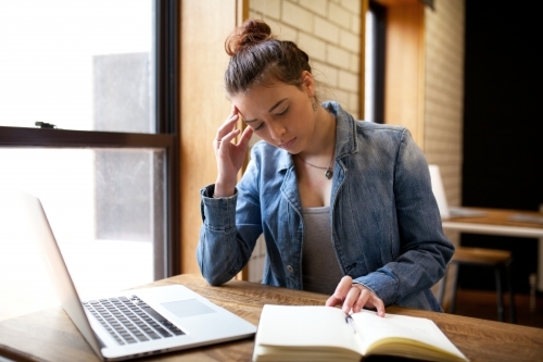 Young woman sitting at a desk in a classroom - Australian Stock Image