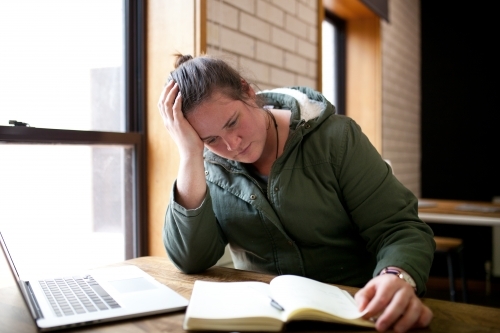 Young woman sitting at a desk in a classroom - Australian Stock Image