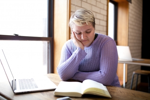 Young woman sitting at a desk in a classroom - Australian Stock Image