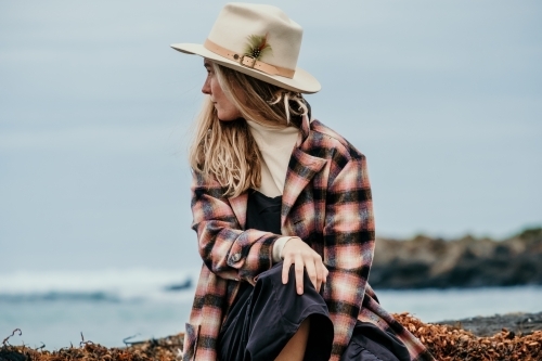 Young woman sitting beside the ocean.