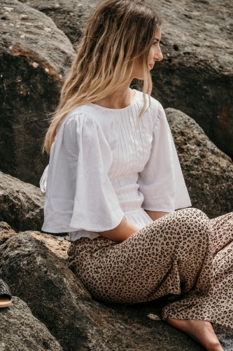 Young woman sitting on a rock cross legged. - Australian Stock Image