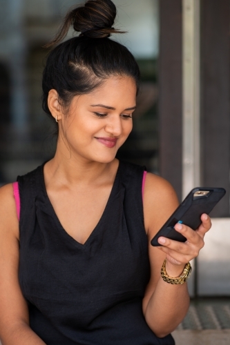 young woman sitting on stairs using phone - Australian Stock Image