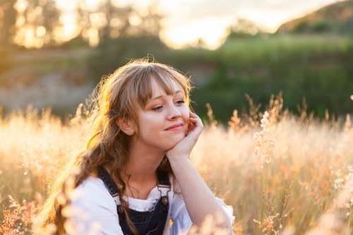 Young woman sitting outside in grass dreaming - Australian Stock Image