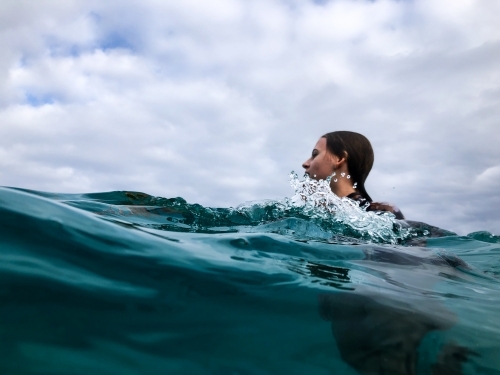 Young woman swimming in ocean on overcast day - Australian Stock Image
