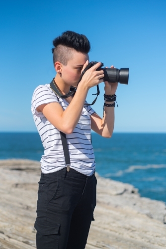 Young woman taking photographs along the coast