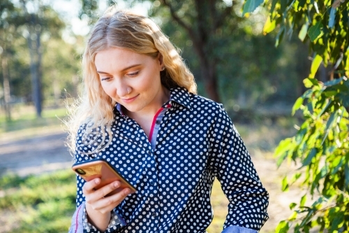 young woman using her mobile phone to keep connected to friends - Australian Stock Image