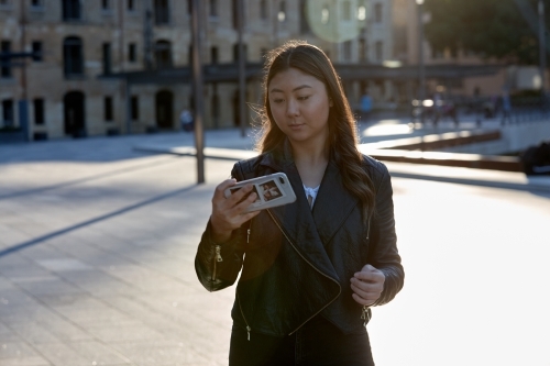 Young woman using mobile phone wearing leather jacket